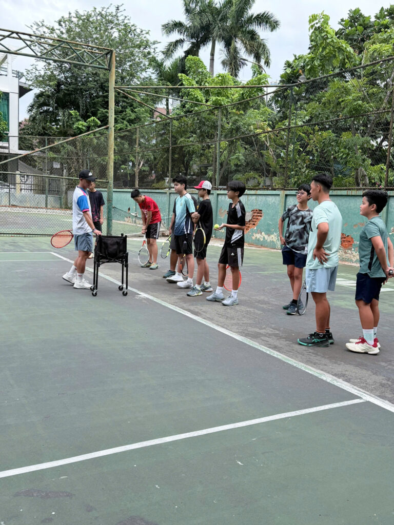 HLV Phan Hoàng Kiệt quan sát nhóm học viên thực hiện bài tập tennis