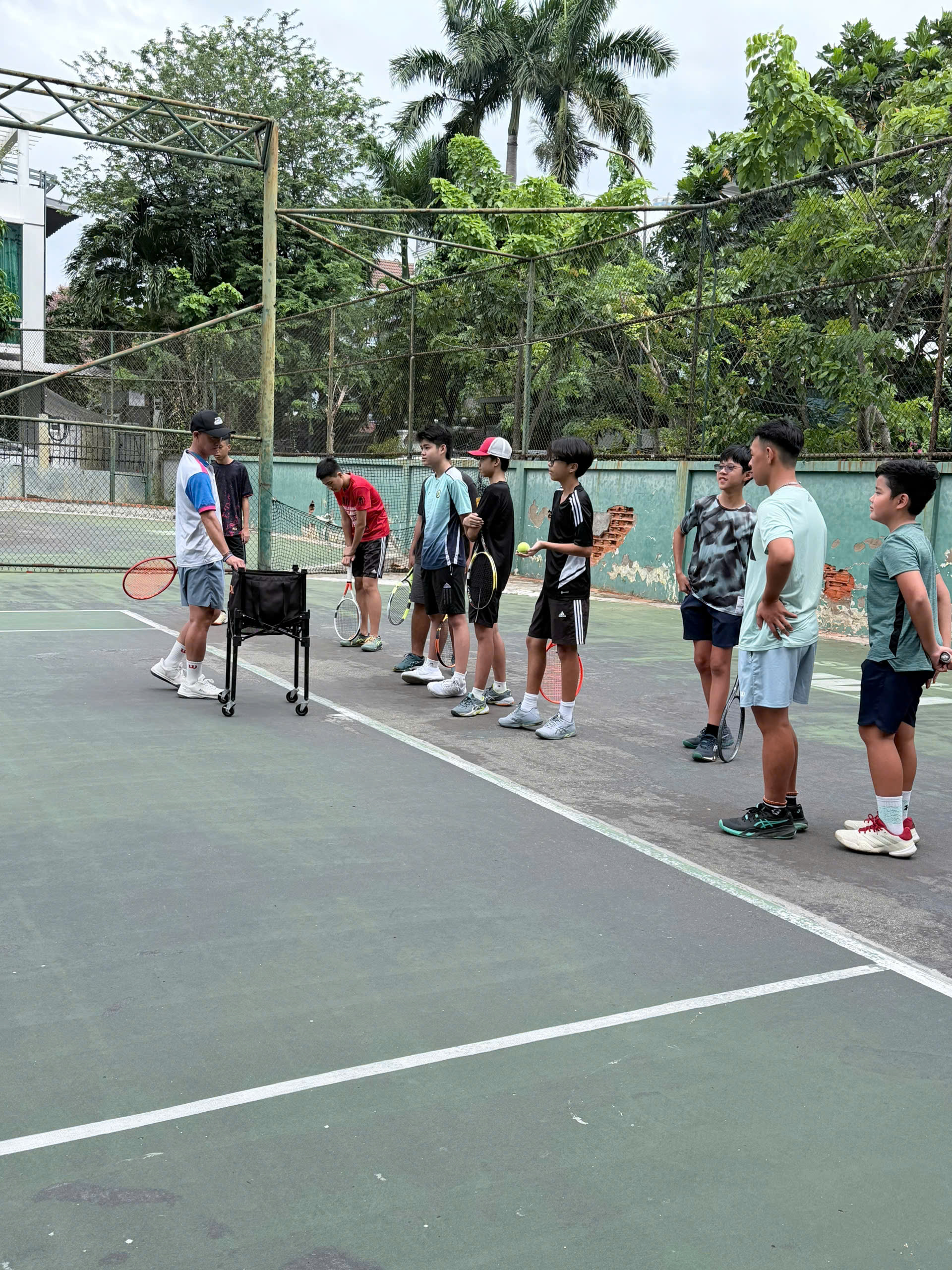 HLV Phan Hoàng Kiệt quan sát nhóm học viên thực hiện bài tập tennis