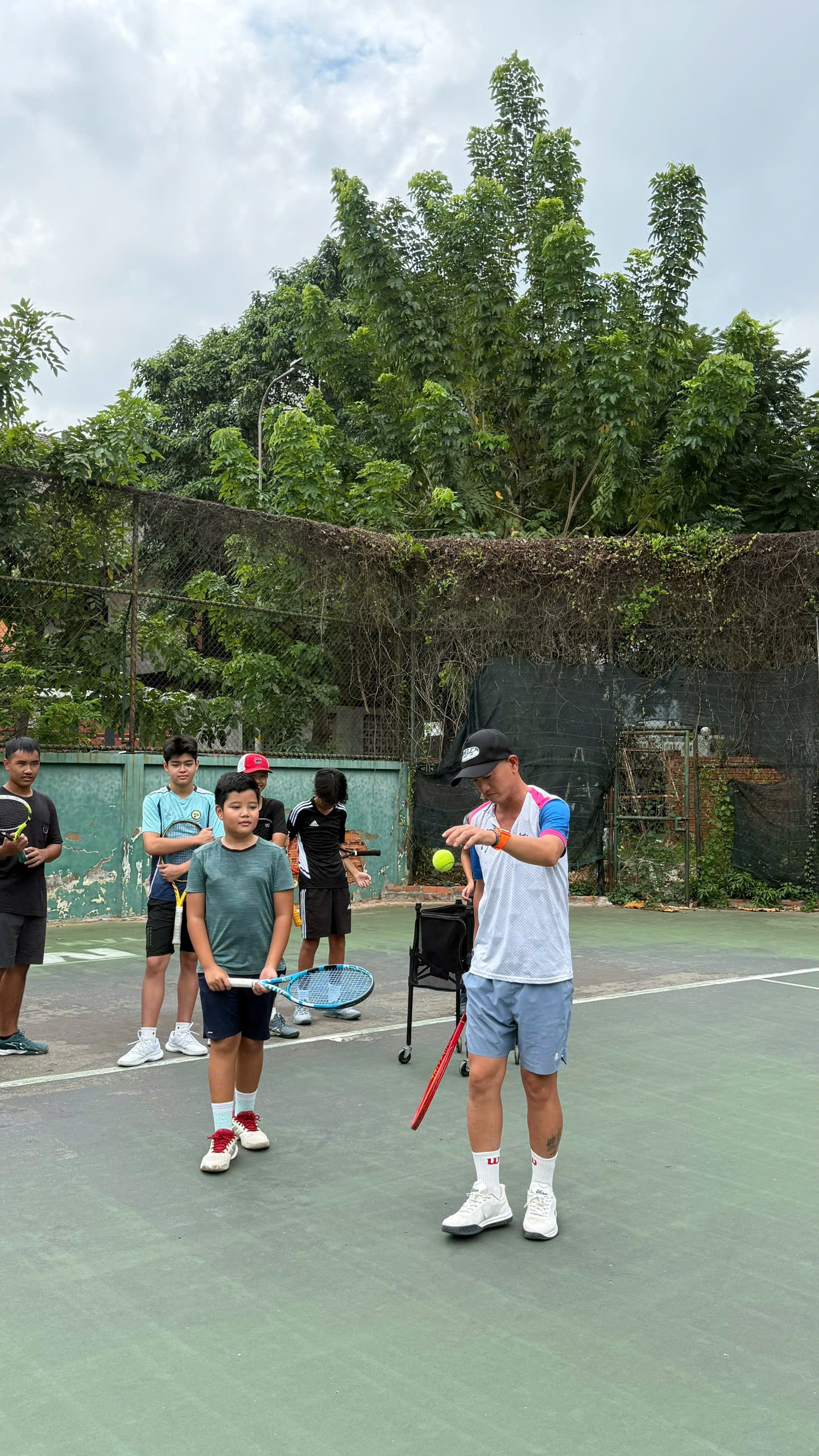 HLV Phan Hoàng Kiệt thị phạm kỹ thuật tennis cho nhóm học viên trẻ