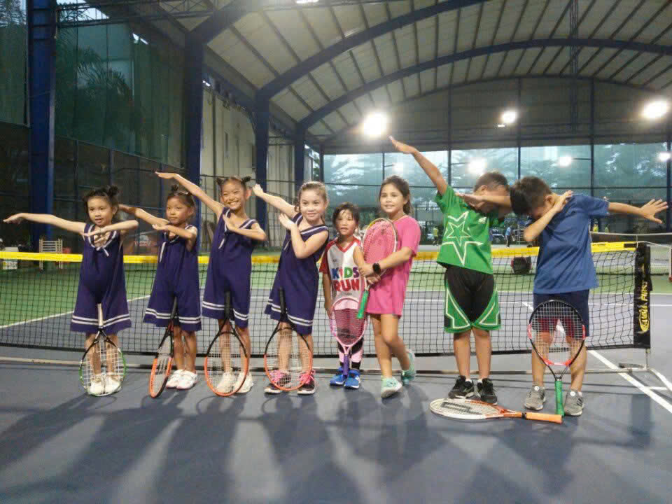 Nhóm trẻ em cầm vợt trong một buổi học tennis
