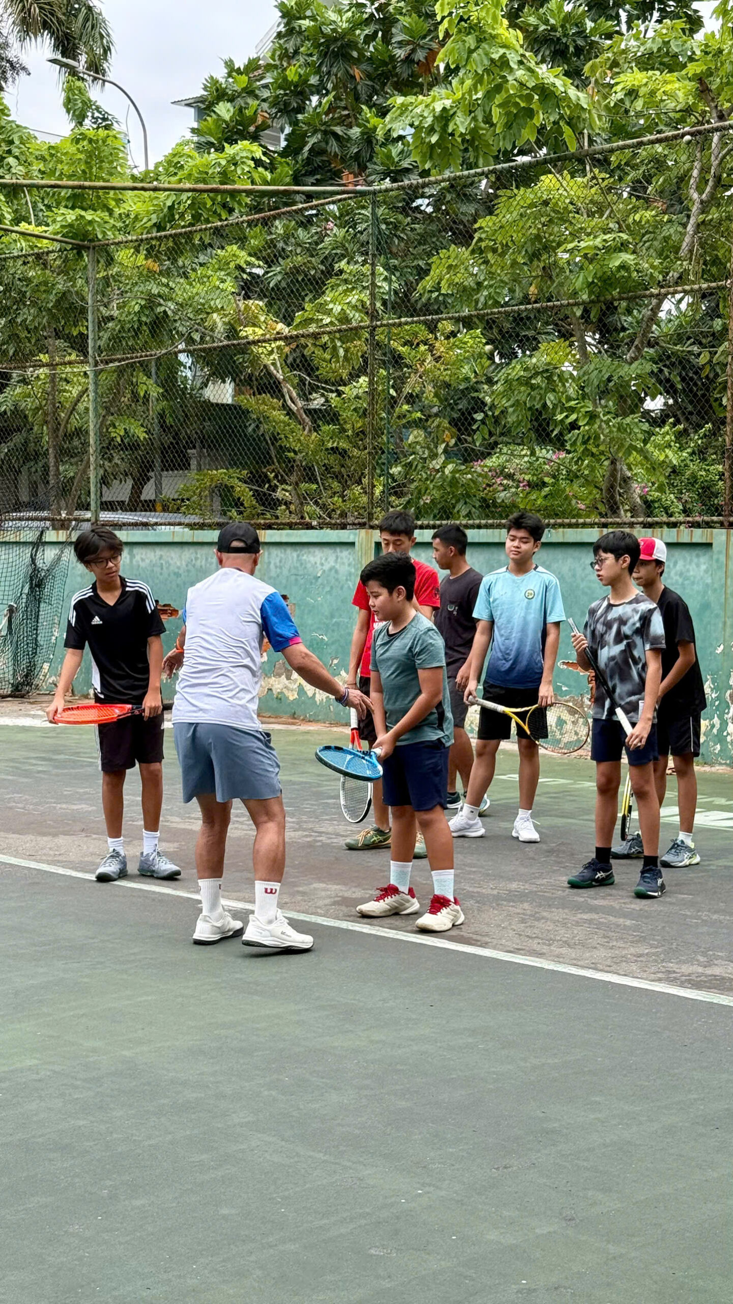 HLV điều chỉnh cách cầm vợt và điểm tiếp xúc cho học viên tennis