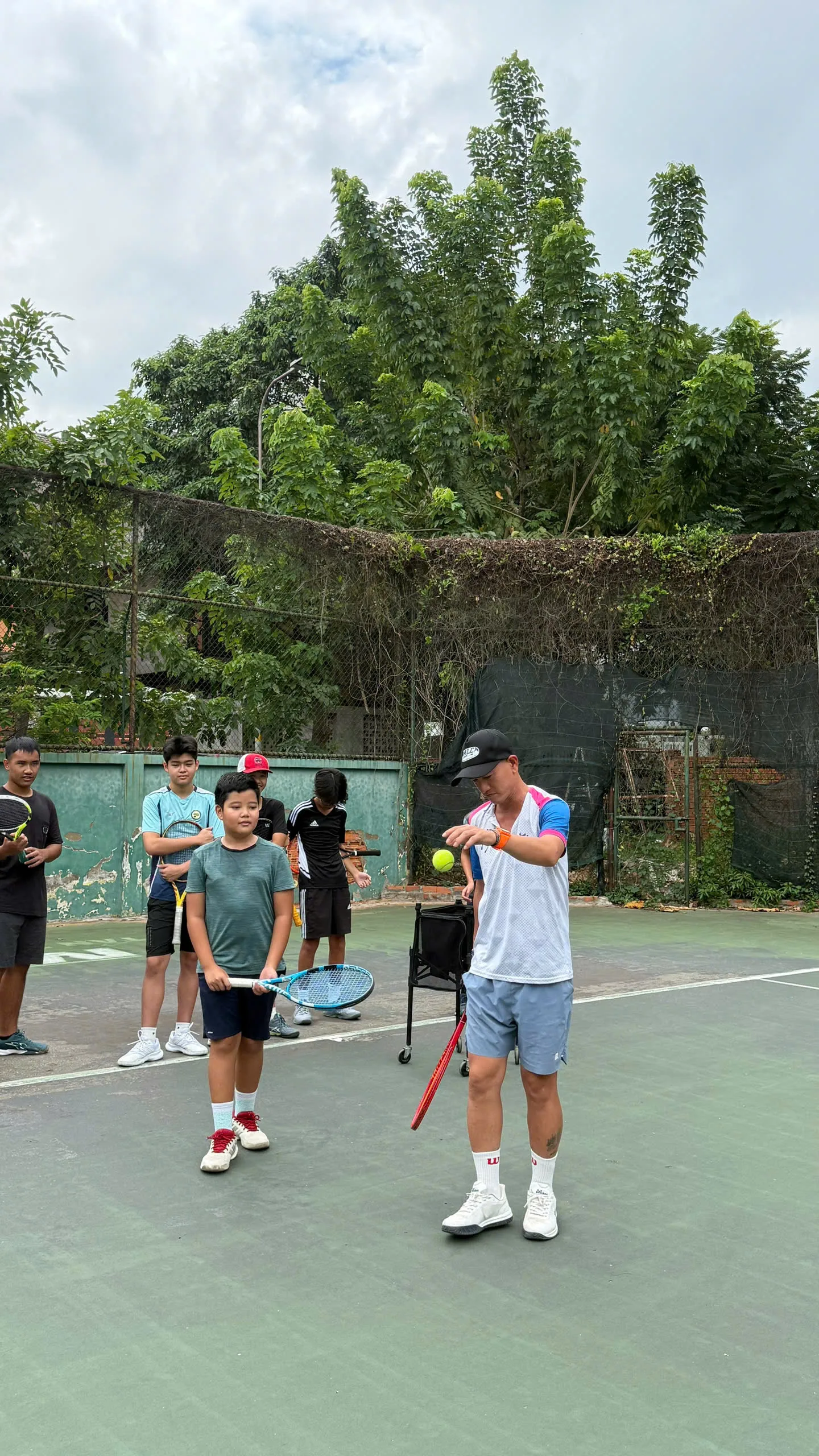 HLV thị phạm điểm tiếp xúc bóng trong buổi học tennis